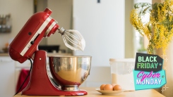 A red stand mixer on a counter with whipped cream on the whisk.