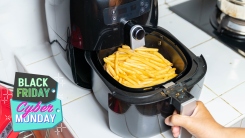 a person pulling open an air fryer with French fries in the basket.