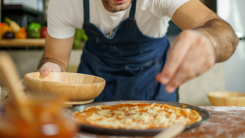 Chef sprinkling cheese on a pizza at home