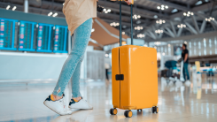 Young female traveler passenger walking with a yellow suitcase at the modern Airport Terminal, Back view of woman on her way to flight boarding gate, Ready for travel or vacation journey