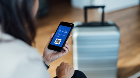 A person looks at a boarding pass on their phone next to luggage